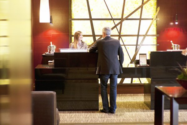 Mature man at reception desk in hotel lobby.